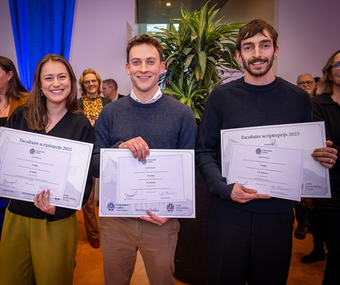 Groepsfoto met vier mannen, waarvan drie studenten die een certificaat omhoog houden. Het zijn de winnaars van de facultaire scriptieprijs 2023-2024 met voormalig voorzitter Bart Krans.